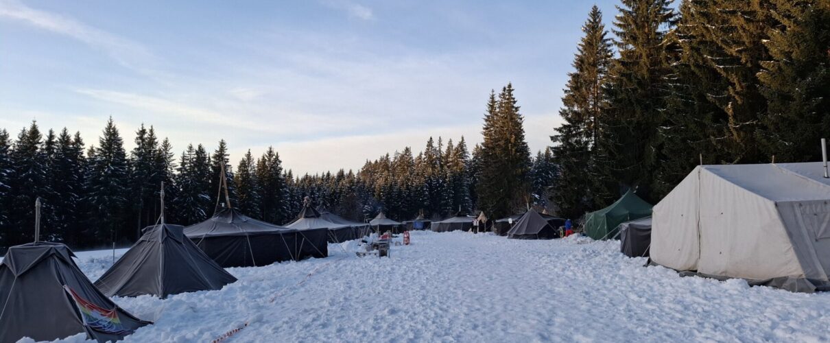 Verschiedene Zelte im Schnee. Oberhalb blauer Himmel